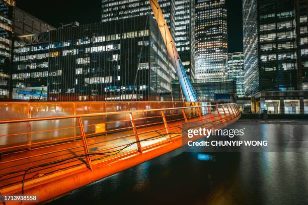 footbridge to canary wharf london's financial district at dusk - london docklands stockfoto's en -beelden