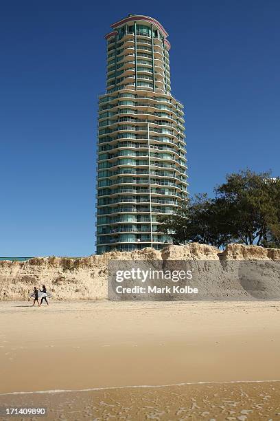 Surfers walk along the beach in front of beach dune erosion at Main Beach Southport on June 24, 2013 on the Gold Coast, Australia. Large sea swells...