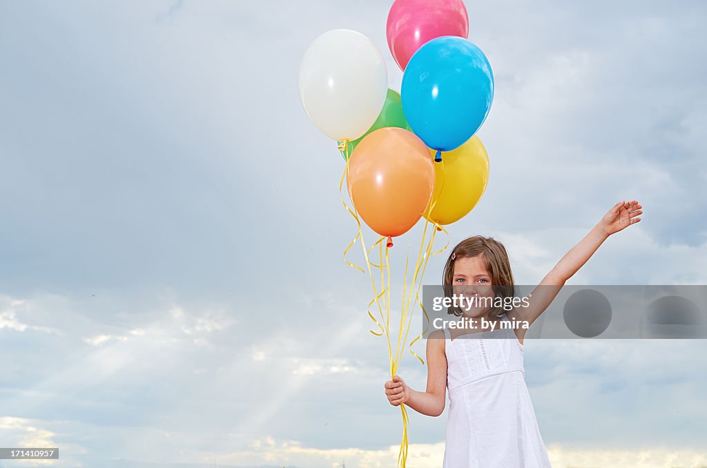 Happy girl with colourful balloons and blue sky