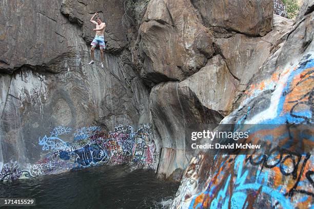 Man jumps off a cliff near graffiti-covered rocks at Sapphire Falls in Cucamonga Canyon on June 23, 2013 in the Angeles National Forest near Rancho...