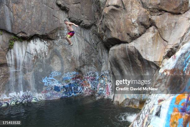 Man jumps off a cliff near graffiti-covered rocks at Sapphire Falls in Cucamonga Canyon on June 23, 2013 in the Angeles National Forest near Rancho...