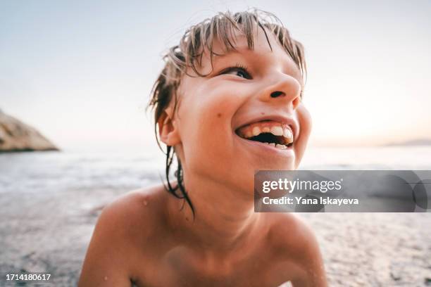 a little boy playing in the waves at the beach on the sunset. childhood memories to cherish - innocence stock pictures, royalty-free photos & images