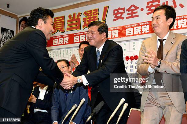 Liberal Democratic Party Secretary General Shigeru ishiba shakes hands with the LDP supporter while Environment Minister Nobuteru Ishihara claps his...