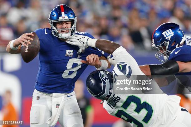 Daniel Jones of the New York Giants is hit by Cameron Young of the Seattle Seahawks during the second half at MetLife Stadium on October 02, 2023 in...