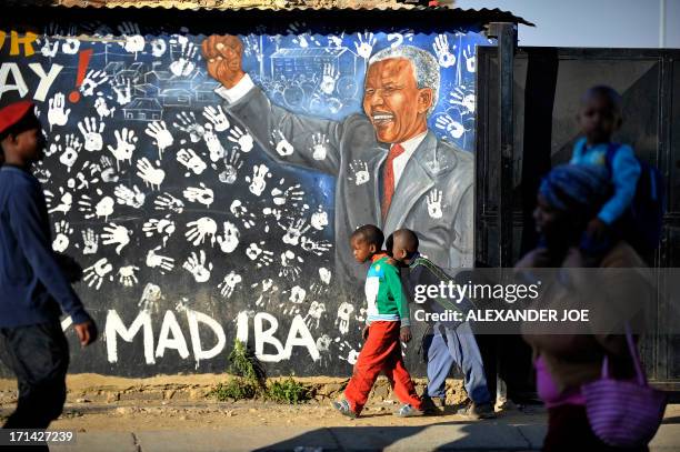 Young Alexandra's residents play near a panting of anti-apartheid icon Nelson Mandela in Soweto, where Mandela once lived, on June 24, 2013. A...