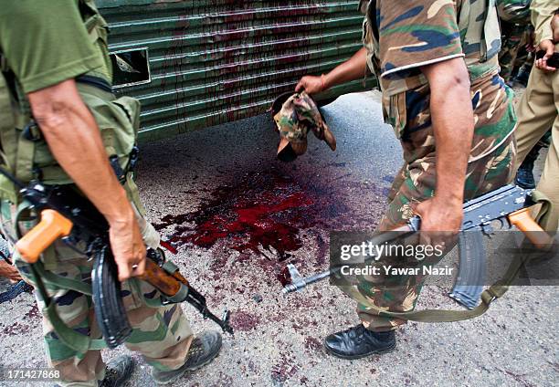 Indian army soldiers lift the caps of their comrades after a militant attack on their convoy on June 24, 2013 in Srinagar, the summer capital of...