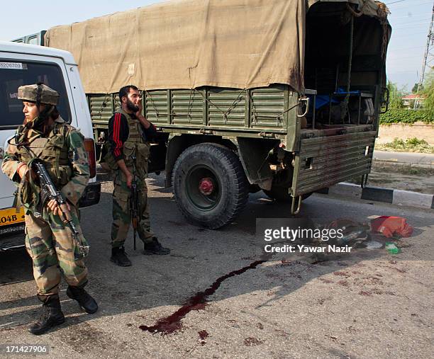 Indian army soldiers stand guard next to their vehicle which came under the attack of rebel militants on June 24, 2013 in Srinagar, the summer...