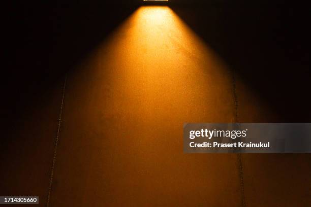 ceiling lights shining down on a iron wall - scheinwerferlichter stock-fotos und bilder