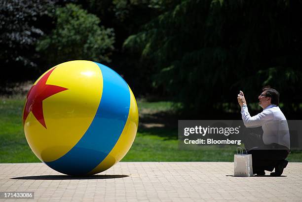 Visitor takes a photograph of a ball displayed outside the Steve Jobs Building at the Pixar Animation Studios headquarters in Emeryville, California,...