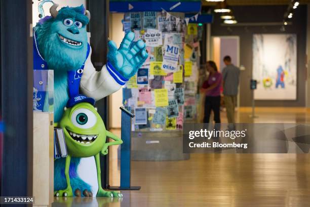 "Monsters University" character cut-outs stand as people walk in the halls at the Pixar Animation Studios headquarters in Emeryville, California,...