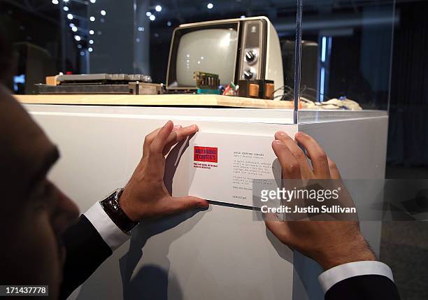 Worker places an information placard on a display of an Apple-1 computer, built in 1976, during the First Bytes: Iconic Technology From the Twentieth...