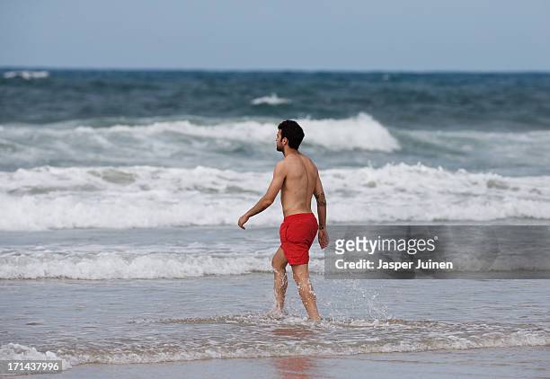 Cesc Fabregas of Spain walks into the sea for a bath at Playa Futuro on June 24, 2013 in Fortaleza, Brazil.