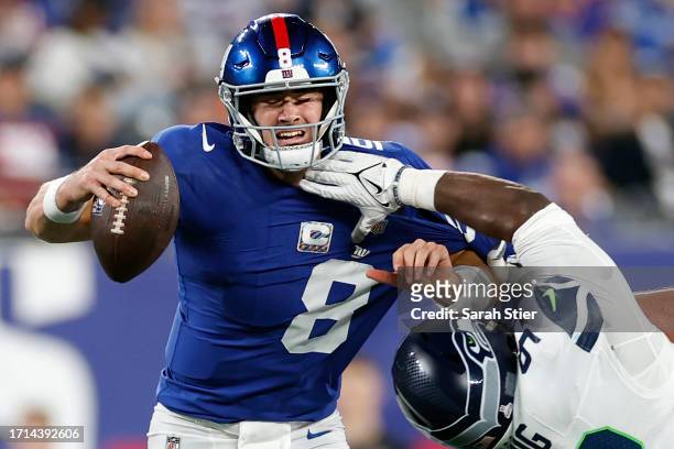Daniel Jones of the New York Giants is hit by Cameron Young of the Seattle Seahawks during the second half at MetLife Stadium on October 02, 2023 in...