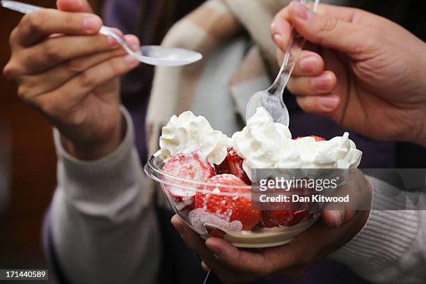 Spectators enjoy a bowl of strawberries and cream on day one of the Wimbledon Lawn Tennis Championships at the All England Lawn Tennis and Croquet...