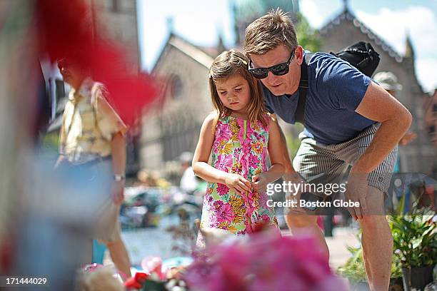 Ava Bowman and her father Brooks, of Los Angeles, Calif., pay their respects. The Boston Marathon bombing memorial at Copley Square is set to close...