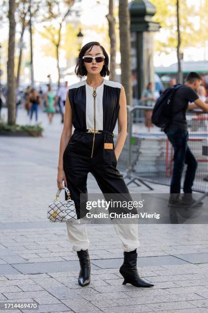 Chriselle Lim wears black white overall, ankle boots, bag outside Louis Vuitton during the Womenswear Spring/Summer 2024 as part of Paris Fashion...