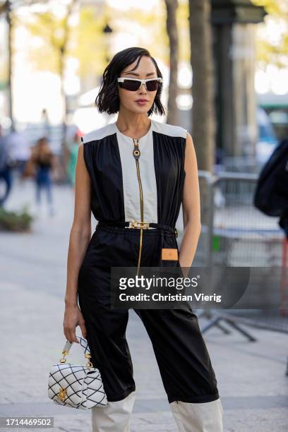 Chriselle Lim wears black white overall, ankle boots, bag outside Louis Vuitton during the Womenswear Spring/Summer 2024 as part of Paris Fashion...