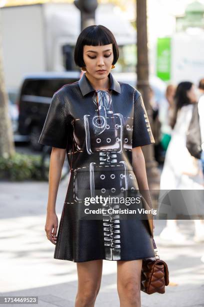 Kiwi Lee Han wears brown bag, ankle boots, black dress with graphic print outside Louis Vuitton during the Womenswear Spring/Summer 2024 as part of...