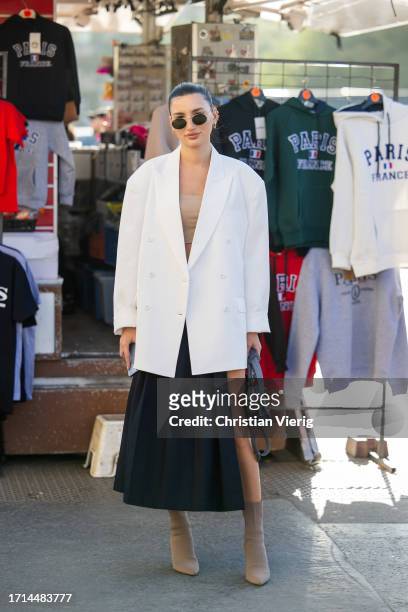 Guest wears white oversized blazer, black pleated skirt with slit outside Rokh during the Womenswear Spring/Summer 2024 as part of Paris Fashion Week...