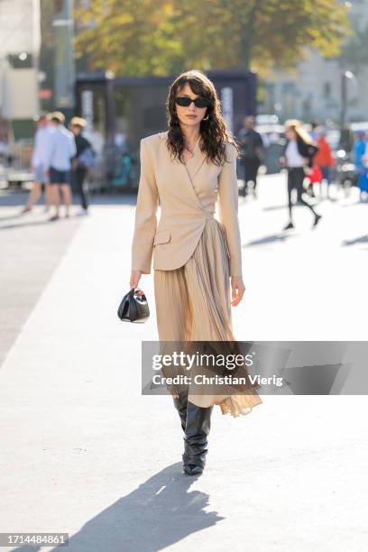 Mary Leest wears beige blazer, pleated skirt, black boots outside Rokh during the Womenswear Spring/Summer 2024 as part of Paris Fashion Week on...