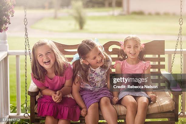 little girls giggling on porch swing - hollywoodschaukel stock-fotos und bilder