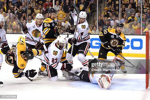 Goalie Corey Crawford of the Chicago Blackhawks reaches to make a save as Tyler Seguin of the Boston Bruins is up ended in front of the net in the...
