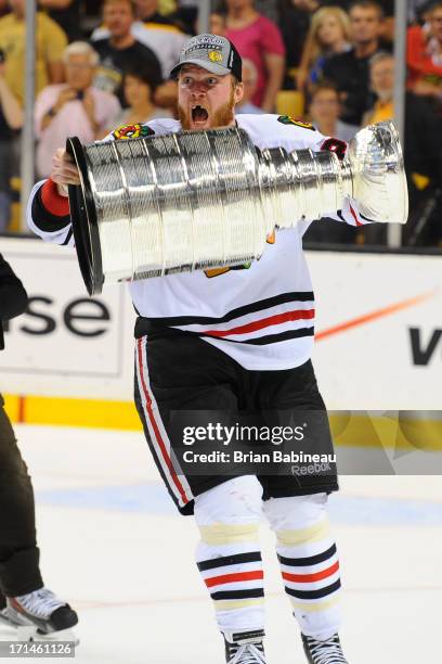 Bryan Bickell of the Chicago Blackhawks hoists the Stanley Cup after the win against the Boston Bruins in Game Six of the Stanley Cup Final at TD...