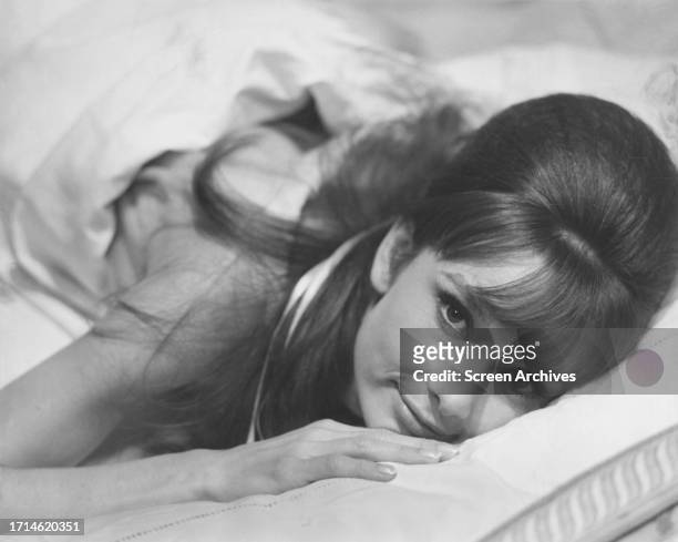Audrey Hepburn lying bare-shouldered in bed in publicity portrait for 1961 'Breakfast at Tiffany's'.