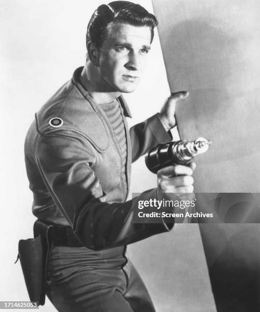 Leslie Nielsen poses for publicity portrait holding phaser weapon for the 1956 sci-fi classic 'Forbidden Planet'.