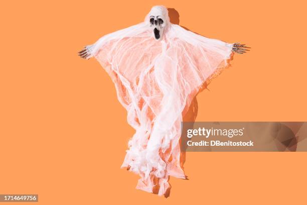 spooky creature with bone hands and ethereal body on orange background. concept of celebration of halloween, ghost, day of the dead, scare, fear, deceased and saints. - sinful pleasures stock-fotos und bilder
