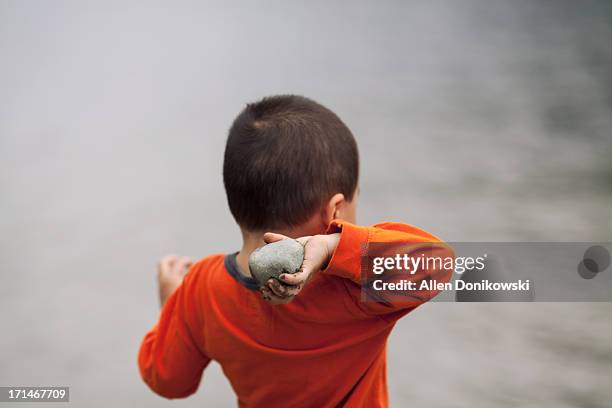 child throwing rock into lake - throwing rocks stock pictures, royalty-free photos & images