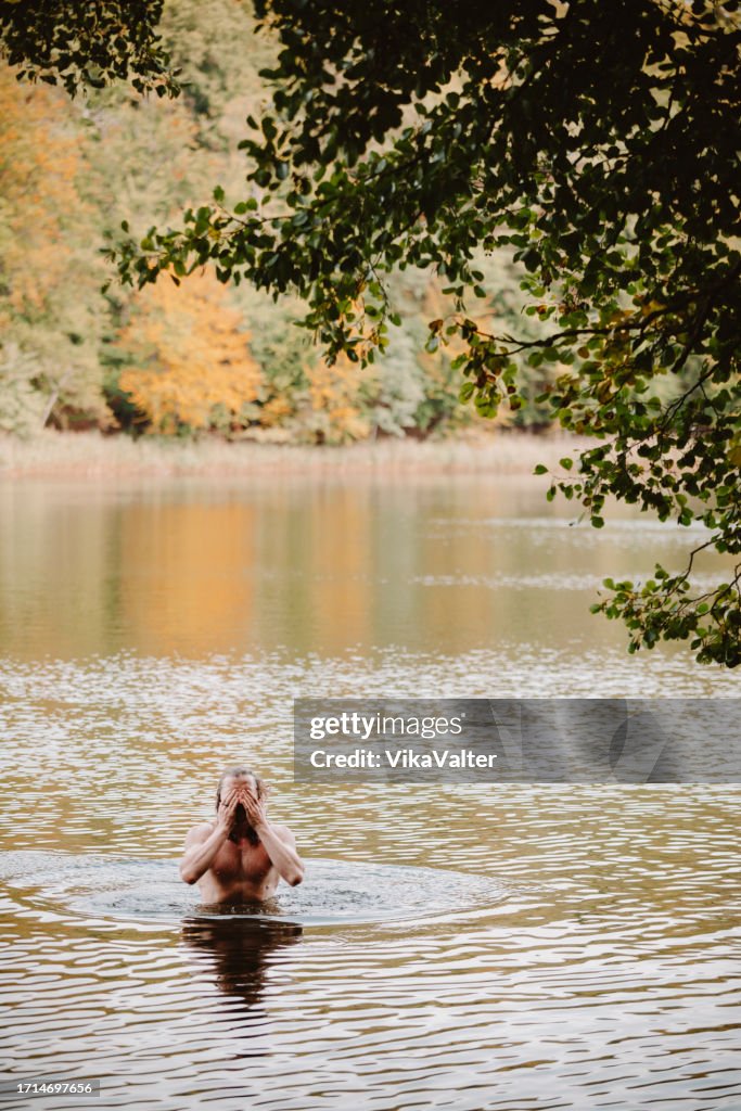 Mann Mitte 40 schwimmt im Herbstsee