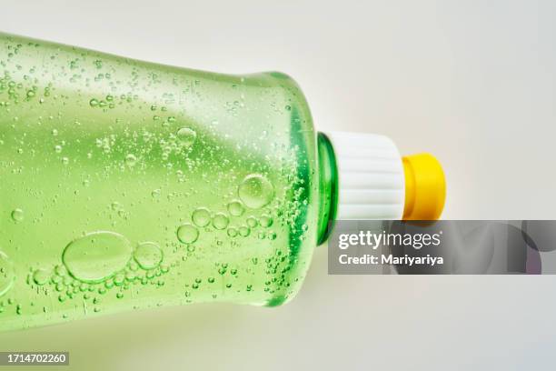 green transparent bottle of dishwashing detergent with bubbles. - spülmittel stock-fotos und bilder