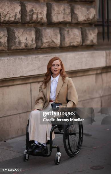 Guest is seen outside Hermes show wearing white classic shirt, beige blazer, vanilla colored cotton long skirt, red Hermes Kelly belt, black Hermes...