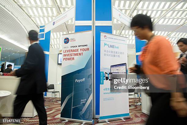 Attendees walk past signage for the London Metal Exchange LMElive, the exchanges real-time price and data system, and Hong Kong Exchanges & Clearing...