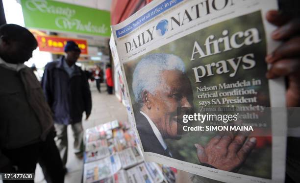 Kenyan man reads a newspaper on June 25,2013 in Nairobi with the front page carrying a headline concerning Nelson Mandela being in a critical...