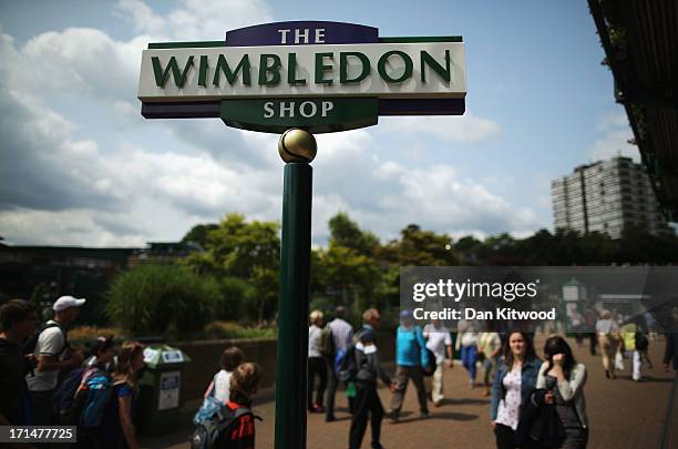 Tennis fans walk past a sign for the Wimbledon shop during day two of the Wimbledon Lawn Tennis Championships at the All England Lawn Tennis and...
