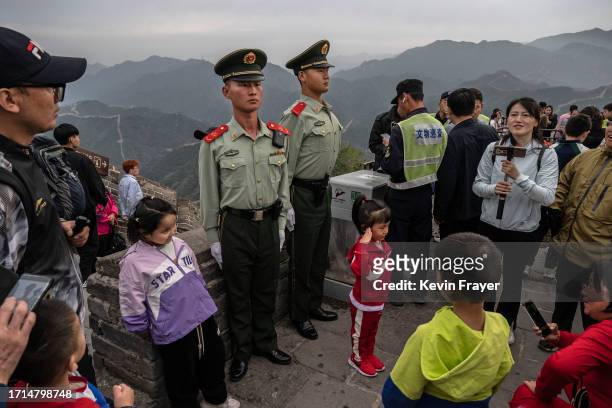 Young girl gives a salute as she stands in front of members of the People's Armed Police working crowd control as she and others visit a section of...