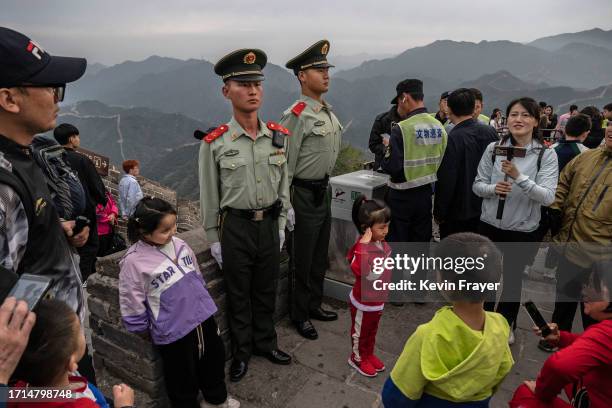 Young girl gives a salute as she stands in front of members of the People's Armed Police working crowd control as she and others visit a section of...