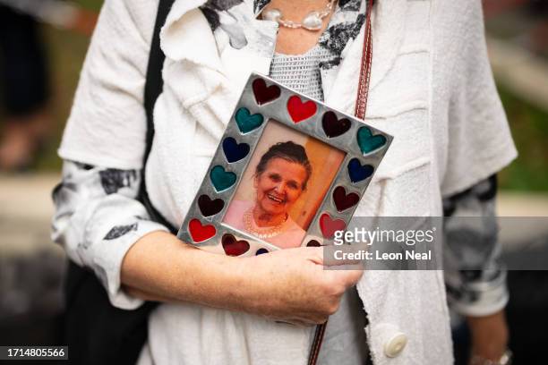 Woman holds a framed photograph of her mother, who died during the pandemic, ahead of the first day of the second phase of the UK Covid-19 public...
