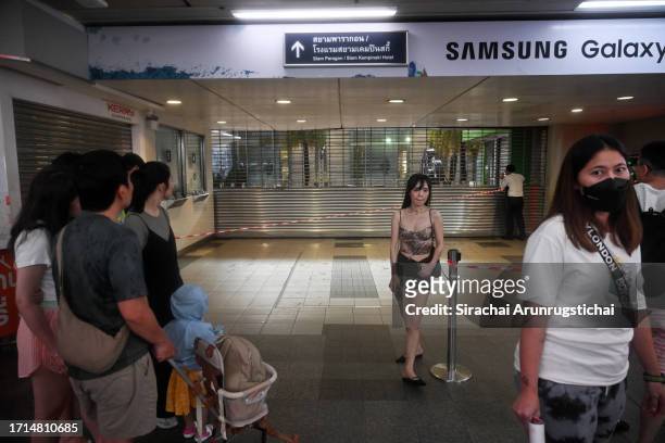People are seen near an entrance to the Siam Paragon mall which has been closed, as a shooting incident was still ongoing inside on October 03, 2023...