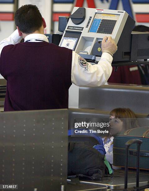 An airport security screener awaits results from an Explosives Trace Detection device as a young traveler, bottom right, looks on January 8, 2003 in...