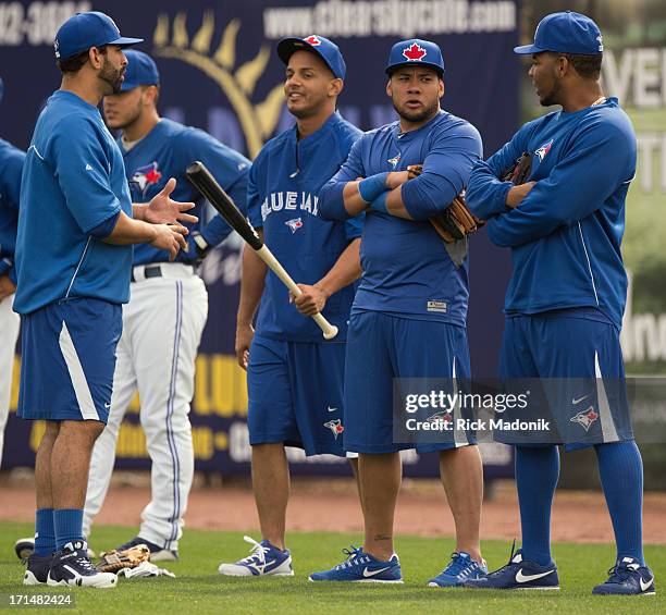 Jose Bautista speaks with Juan Perez and Melky Cabrera and Luis Perez, as they hang out in the outfield while others swat balls during batting...