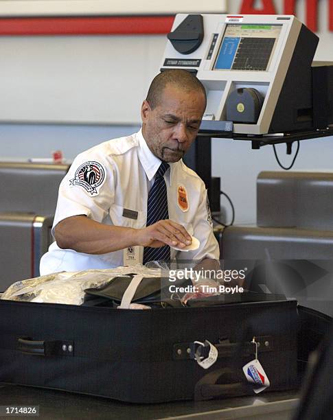 An airport security screener collects luggage samplings to later input into an Explosives Trace Detection device, top , January 8, 2003 in Terminal 3...