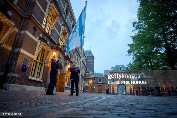 Employees raise the flag of Israel at the entrance to Ministry of General Affairs in the Binnenhof in The Hague, on October 9 to show support for...