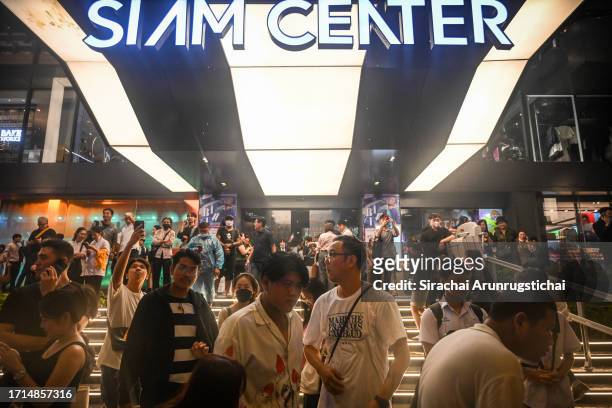 People stand near the Siam Center, next to the Siam Paragon mall after being evacuated from the Paragon as a shooting incident was still ongoing...