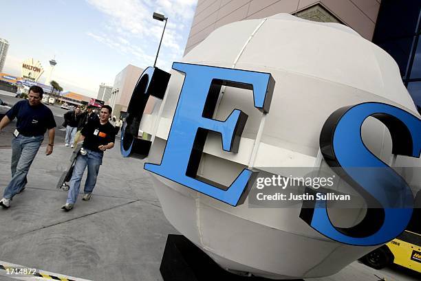 People pass by a CES sign in front of the Las Vegas Convention Center as preparations continue for the 2003 International CES January 8, 2003 in Las...