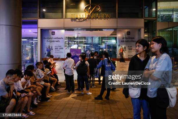People gather outside the Siam Paragon mall after being evacuated as a shooting incident was still ongoing inside on October 03, 2023 in Bangkok,...