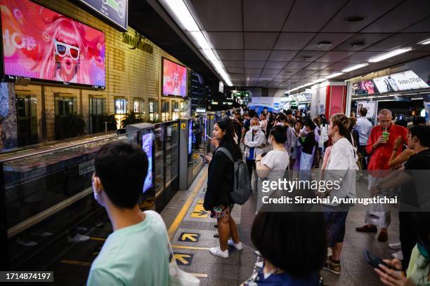 People are seen on a platform of the Siam BTS Skytrain station, which faces the Siam Paragon mall, as the mall was being evacuated while a shooting...