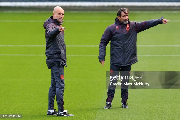 Pep Guardiola, Manager of Manchester City speaks with coach, Lorenzo Buenaventura during a training session ahead of their UEFA Champions League...